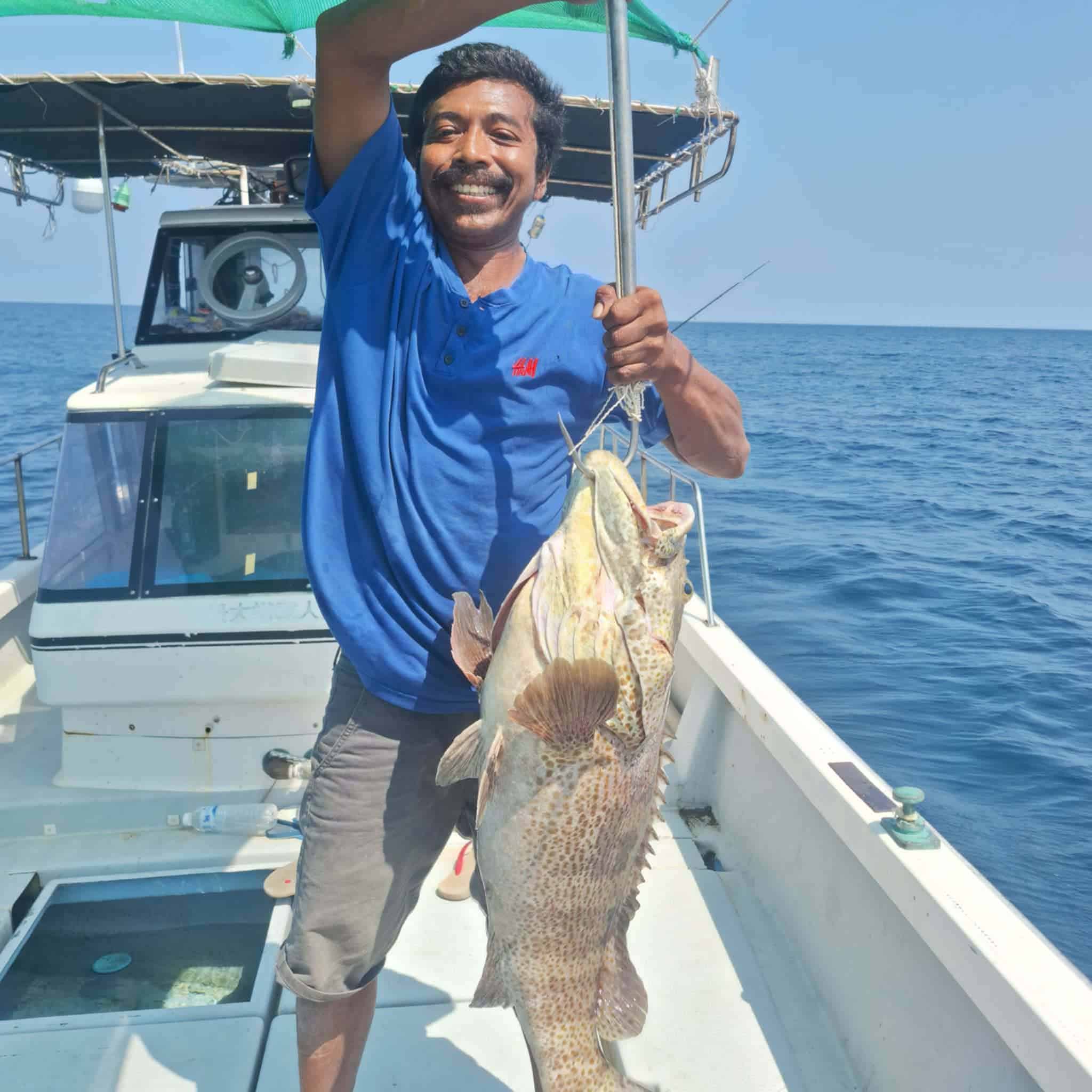 Local fishing guide holding a net catch on a Koh Tao boat
